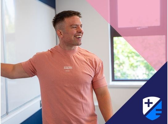 Teacher David Lewis smiling in front of a whiteboard