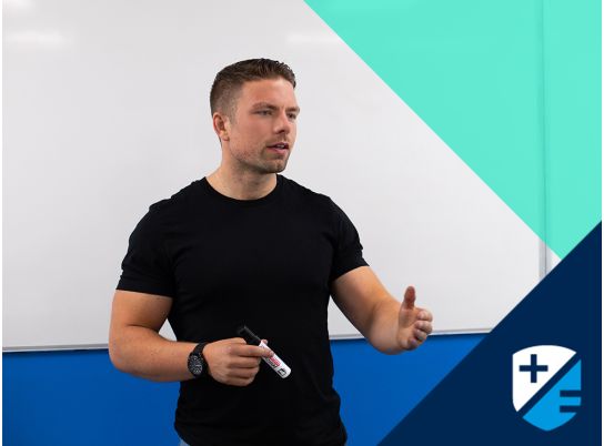 Teacher Dave Lewis speaking in front of a whiteboard