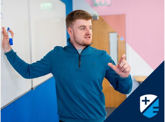 Teacher David Langley speaking in front of a whiteboard