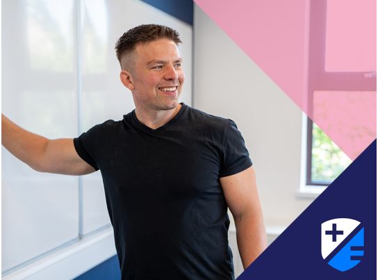 Teacher David Lewis smiling in front of a whiteboard