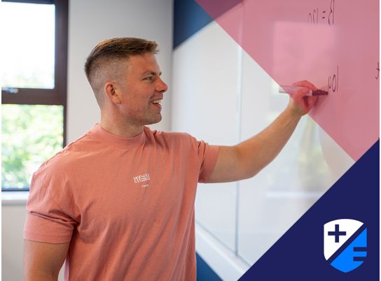 Teacher David Lewis writing on a whiteboard 