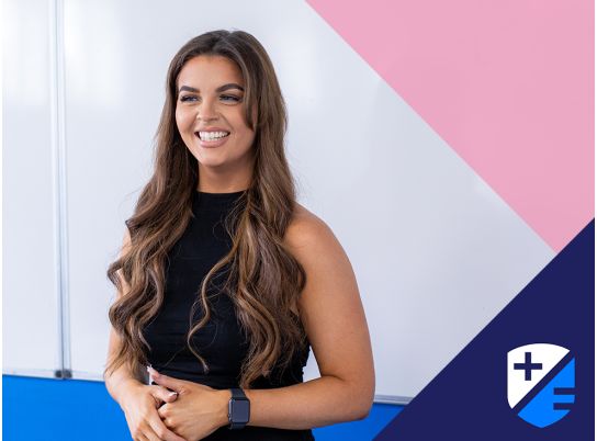 Teacher Katie smiling in front of a whiteboard