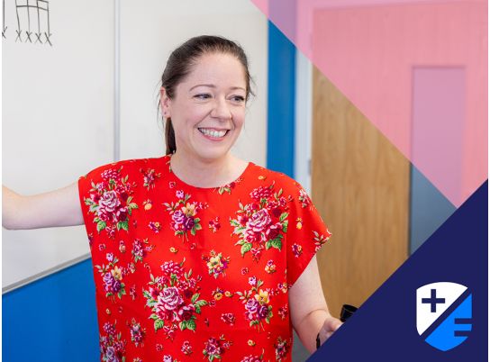 Teacher Lynda smiling in front of a whiteboard
