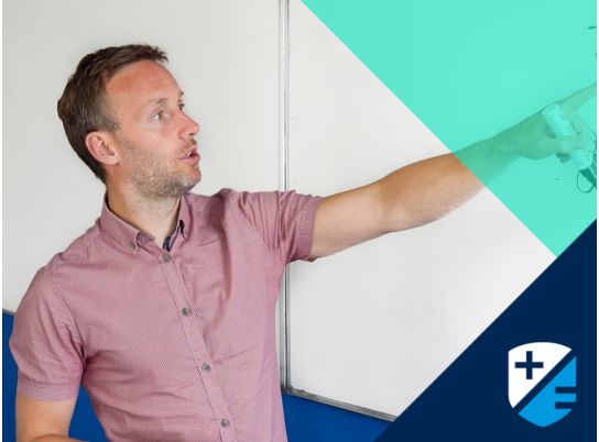 Teacher Carl Brien pointing to a whiteboard