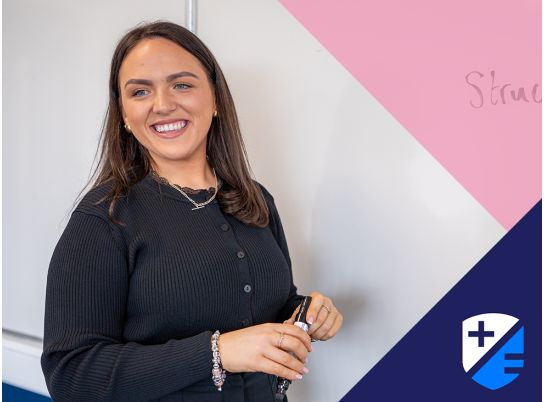 Teacher Megan smiling in front of a whiteboard