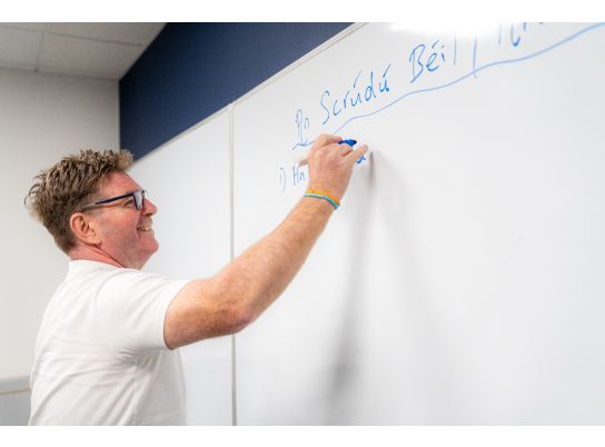 Sean writing in Irish on a whiteboard