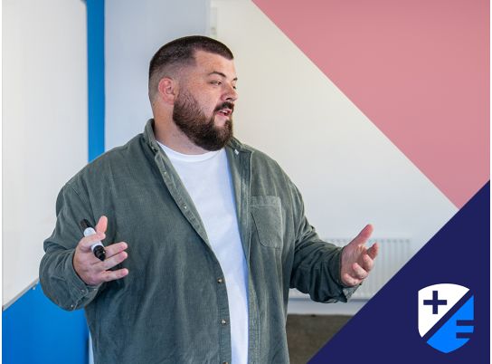 Teacher Thomas Maher speaking in front of a whiteboard